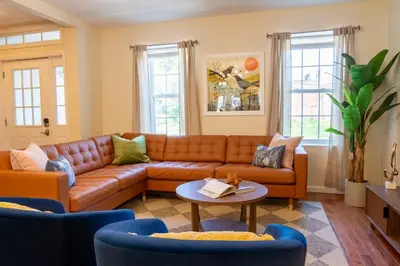 a living room with a brown couch and blue chairs at Downtown Albany, Hot Tub, Game Room, eV Charger in Albany
