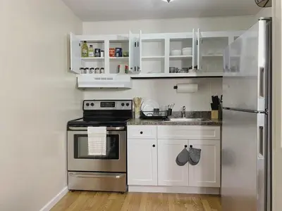 a kitchen with white cabinets and a stainless steel refrigerator at Premium convenient stays in Manchester