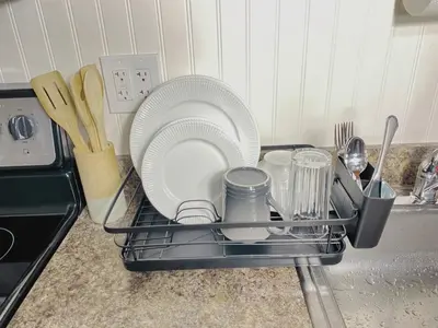 a dish drying rack with plates and utensils in a kitchen at Premium convenient stays in Manchester