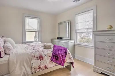 a bedroom with a bed and a dresser and two windows at Charming Mamaroneck with 3BR and 3BA 22 Mi to Manhattan in Mamaroneck