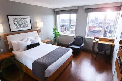 a hotel room with a bed and a desk and windows at Edge Hotel Washington Heights in New York