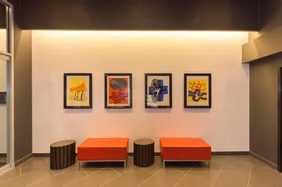 a room with three stools and four paintings on a wall at Edge Hotel Washington Heights in New York