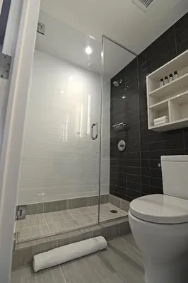 a bathroom with a toilet and a glass shower at Edge Hotel Washington Heights in New York