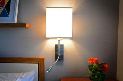 a lamp attached to a wall with a vase of flowers at Edge Hotel Washington Heights in New York