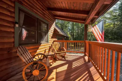 a porch of a cabin with benches on it at Secluded Log Cabin with Hot Tub Fire Pit Game Room in Newfoundland