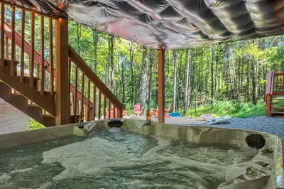 a hot tub on the back porch of a house at Secluded Log Cabin with Hot Tub Fire Pit Game Room in Newfoundland