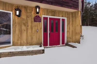 a red door on a cabin in the snow at The Mahogany Villa Indoor pool Spa Sauna Gameroom in Dover