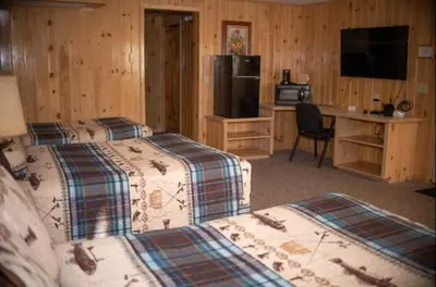 a bedroom with three beds and a desk with a computer at Smith's Colonial Motel in Hancock