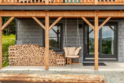 a cabin with a pile of fire wood next to a chair at The Greylock Cabin in Florida