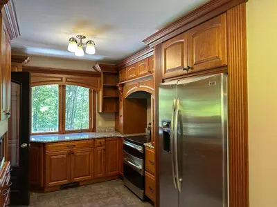 a kitchen with wooden cabinets and a stainless steel refrigerator at Charlemont Chalet - A 15 Acre Private Retreat in Charlemont