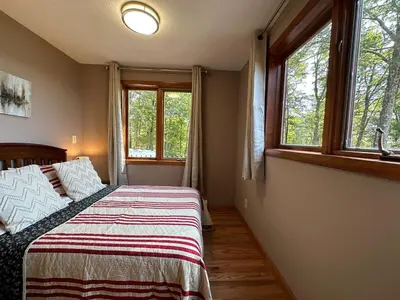 a bedroom with a bed and two windows at Charlemont Chalet - A 15 Acre Private Retreat in Charlemont