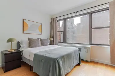 a bedroom with a bed and a large window at Blueground Midtown East view nr UN Plaza NYC-2114 in New York