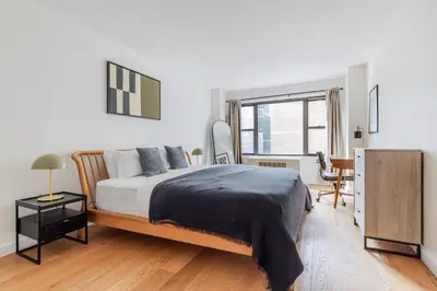 a bedroom with a bed and a desk and a window at Blueground Midtown East view nr UN Plaza NYC-2114 in New York