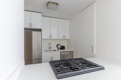 a kitchen with white cabinets and stainless steel appliances at Blueground Midtown East view nr UN Plaza NYC-2114 in New York
