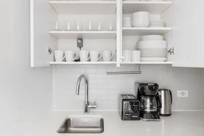a kitchen counter with a sink and white cabinets at Blueground Midtown East rooftop nr Bryant Park NYC-2070 in New York