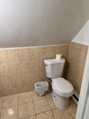 a bathroom with a toilet and a trash can at BedRoom with half bathroom in Ridgefield Park