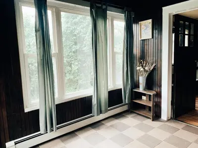 a room with windows with green curtains and a table at The Mountain House in Lanesville