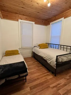 two beds in a room with wood floors and windows at The Mountain House in Lanesville