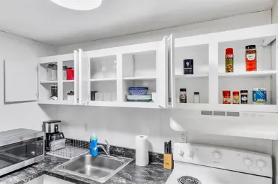 a kitchen with white cabinets and a sink at TruStay in Central Connecticut in Manchester