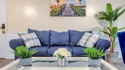 a blue couch in a living room with plants at TruStay in Central Connecticut in Manchester
