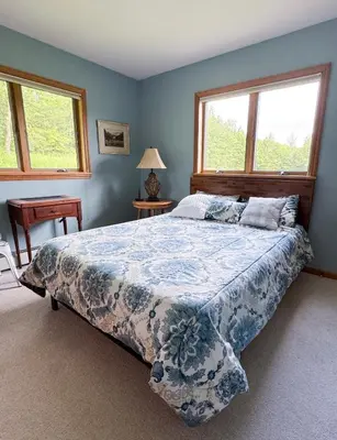 a bedroom with a large bed and two windows at Mountain Retreat in the Catskills in Roxbury