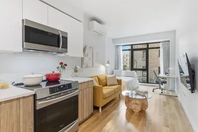 a kitchen and living room with a stove and a couch at Elegant Studio Apartment in Steinway