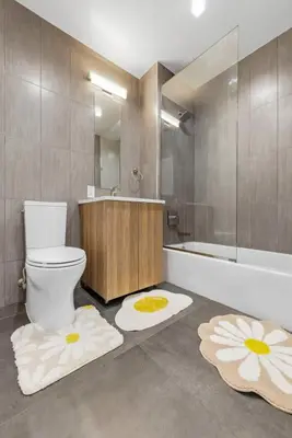 a bathroom with a toilet and a tub with rugs at Elegant Studio Apartment in Steinway