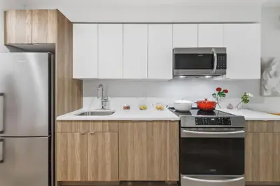 a kitchen with white cabinets and a stove and refrigerator at Elegant Studio Apartment in Steinway
