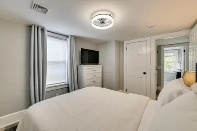 a bedroom with a white bed and a television at 2 Mi to Uptown Centrally Located Kingston Apt! in Kingston