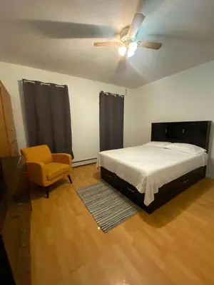 a bedroom with a bed and a ceiling fan and a chair at Private Room near NYC! in Paterson