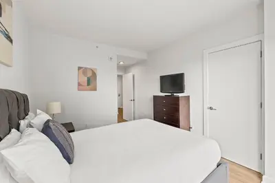 a white bedroom with a bed and a tv at Luxury Modern Apartment Near Stamford Station in Stamford