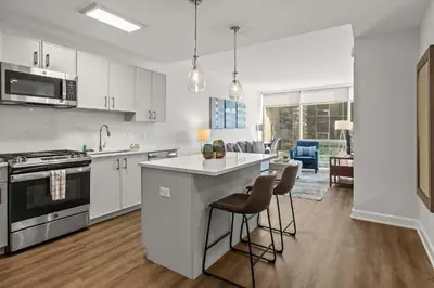 a kitchen with white cabinets and a table and chairs at Luxury Modern Apartment Near Stamford Station in Stamford