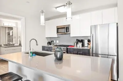 a kitchen with white cabinets and a stainless steel refrigerator at Luxury Urban Escape Walk to Downtown in Stamford