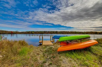 a couple of boats sitting on the shore of a lake at Lakefront Pocono Retreat with Hot Tub and Movie Hub in Pocono Summit