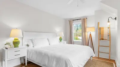 a white bedroom with a white bed and a window at Modern Berkshires Farmhouse w Porch Fireplace Views Beaver Creek by AvantStay in Stockbridge