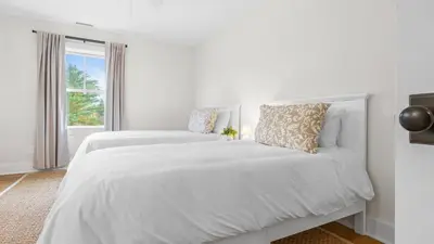 a white bedroom with two beds and a window at Modern Berkshires Farmhouse w Porch Fireplace Views Beaver Creek by AvantStay in Stockbridge