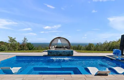 a swimming pool with two chairs and an infinity at Pinnacle Pointe by Relaxtay 600 Acre Private Luxury Estate with Spa, Pool, Theater and Lake in Middletown