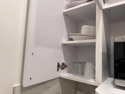 a white cupboard with plates and dishes in it at Room with Kitchen in Chelsea - Shared Bathroom - 3rd Floor Walk-UP in New York