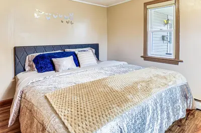 a bedroom with a bed with a blue and white comforter at 1 Mi to Main St Riverside Torrington Apt with Yard in Torrington