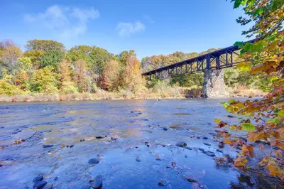a train bridge over a river with trees in the background at Riverfront Apt with Fire Pit and Yard in Millers Falls