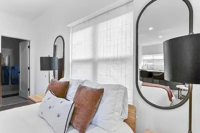 a bedroom with a white bed with pillows and a mirror at Harbor Haven, Apt #1 Studio in Stamford