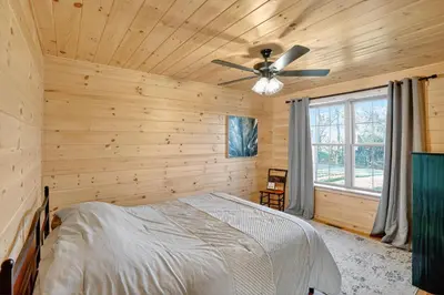 a log cabin bedroom with a bed and a ceiling fan at Peaceful Lakefront Cabin in the Catskills cabin in Athens