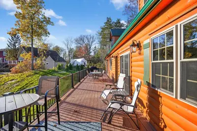 a deck with chairs and tables on a house at Peaceful Lakefront Cabin in the Catskills cabin in Athens