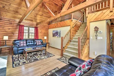 a living room with a couch and a staircase in a cabin at Log Cabin and Suites Close to Elk Mountain Ski Resort in Pleasant Mount