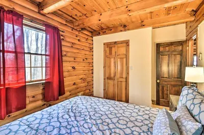 a bedroom with a bed in a room with wooden walls at Log Cabin and Suite, Friendly Retreat Close to Skiing in Pleasant Mount