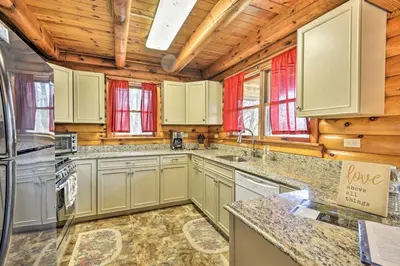 a kitchen with white cabinets and wooden walls at Log Cabin and Cottage Near Elk Mountain Ski Slopes in Pleasant Mount