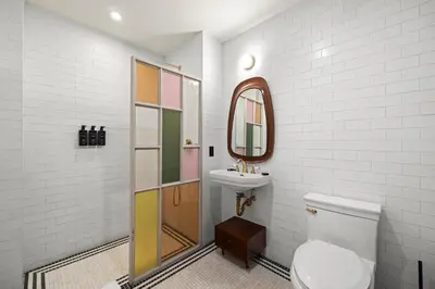 a bathroom with a toilet and a sink and a mirror at Freeman 303 by Rove Travel - 1BR Condo with Shared Amenities in New York