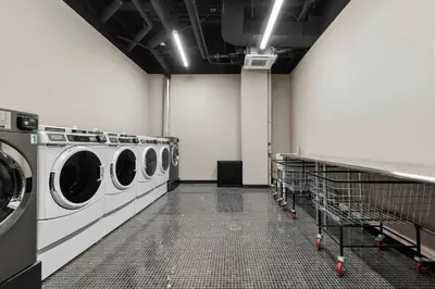 a laundry room with three washing machines in it at Freeman 303 by Rove Travel - 1BR Condo with Shared Amenities in New York