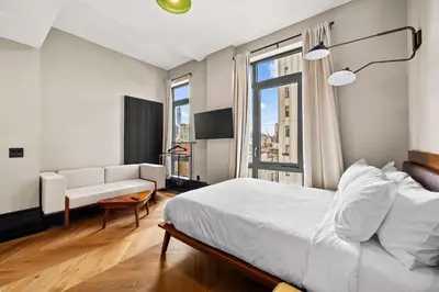 a bedroom with a bed and a couch and a window at Freeman 701 by Rove Travel - Studio with Shared Amenities in New York