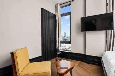 a bedroom with a bed and a chair and a tv at Freeman 1001 by Rove Travel - Studio with Shared Amenities in New York
